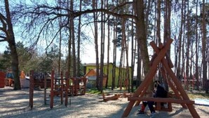 A playground with wooden structures and a yellow building in the background.
