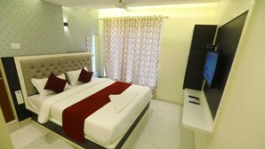 Ein Hotelzimmer mit einem großen Bett, einem Fernseher und einem Vorhang.