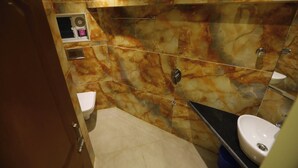 Ein Badezimmer mit Marmorwänden, Toilette, Waschbecken und Dusche.