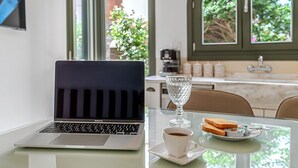 Um laptop sobre uma mesa com um copo de água, uma xícara de café e um prato com torradas e manteiga.