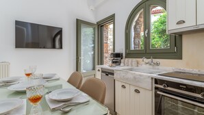 Cozinha moderna com área de refeições, uma cafeteira Bosch e uma grande janela com vista para o verde.