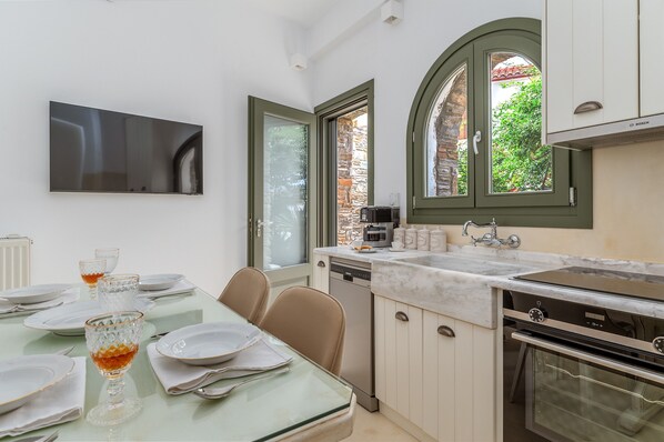 A modern kitchen with a dining area, a Bosch coffee maker, and a large window with a view of greenery.
