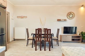 Ein Essbereich mit Tisch, Stühlen, einem Fernseher und einer Heizung.