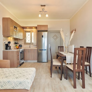 Eine moderne Küche mit Holzschränken, einem Edelstahlkühlschrank und einem Essbereich mit Tisch und Stühlen.