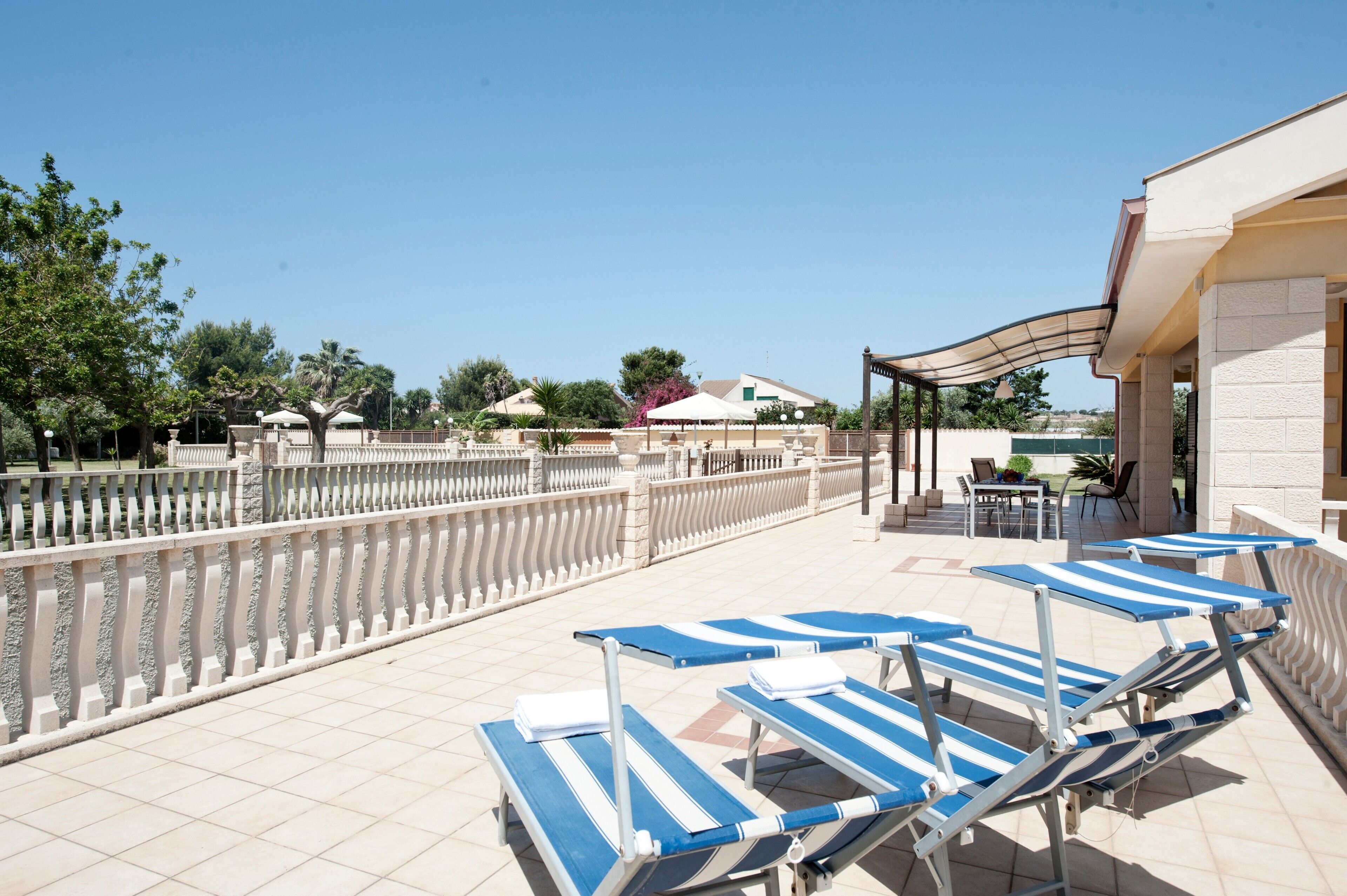 Eine Dachterrasse mit Liegestühlen, einer überdachten Lounge und Blick auf die umliegende Landschaft.