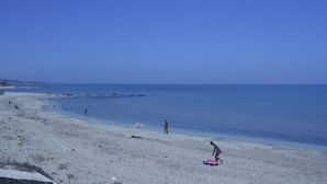 Ein Strand mit blauem Himmel, ruhiger See und einigen Personen.