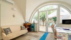 Een kamer met een bank, een klein tafeltje, een televisie en een groot rondboogvenster.