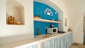Een keuken met een wit aanrecht, een spoelbak, een magnetron en een fornuis. Er zijn decoratieve items aan de muur en een blauwe accentmuur.