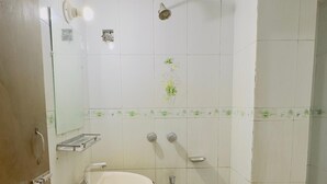 A bathroom with a sink, mirror, shower, and tiled walls. - Mohammadia Restaurant & Guest House (Dhaka)