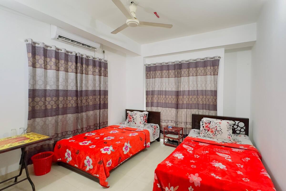 Ein Zimmer mit zwei Einzelbetten, einem Schreibtisch und einem Stuhl.