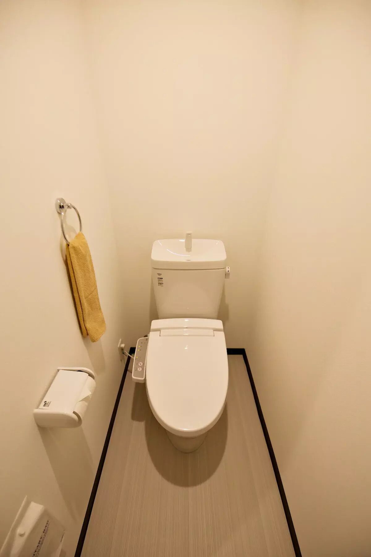 Ein kleines, sauberes Badezimmer mit Toilette, Handtuchhalter und Toilettenpapierhalter.