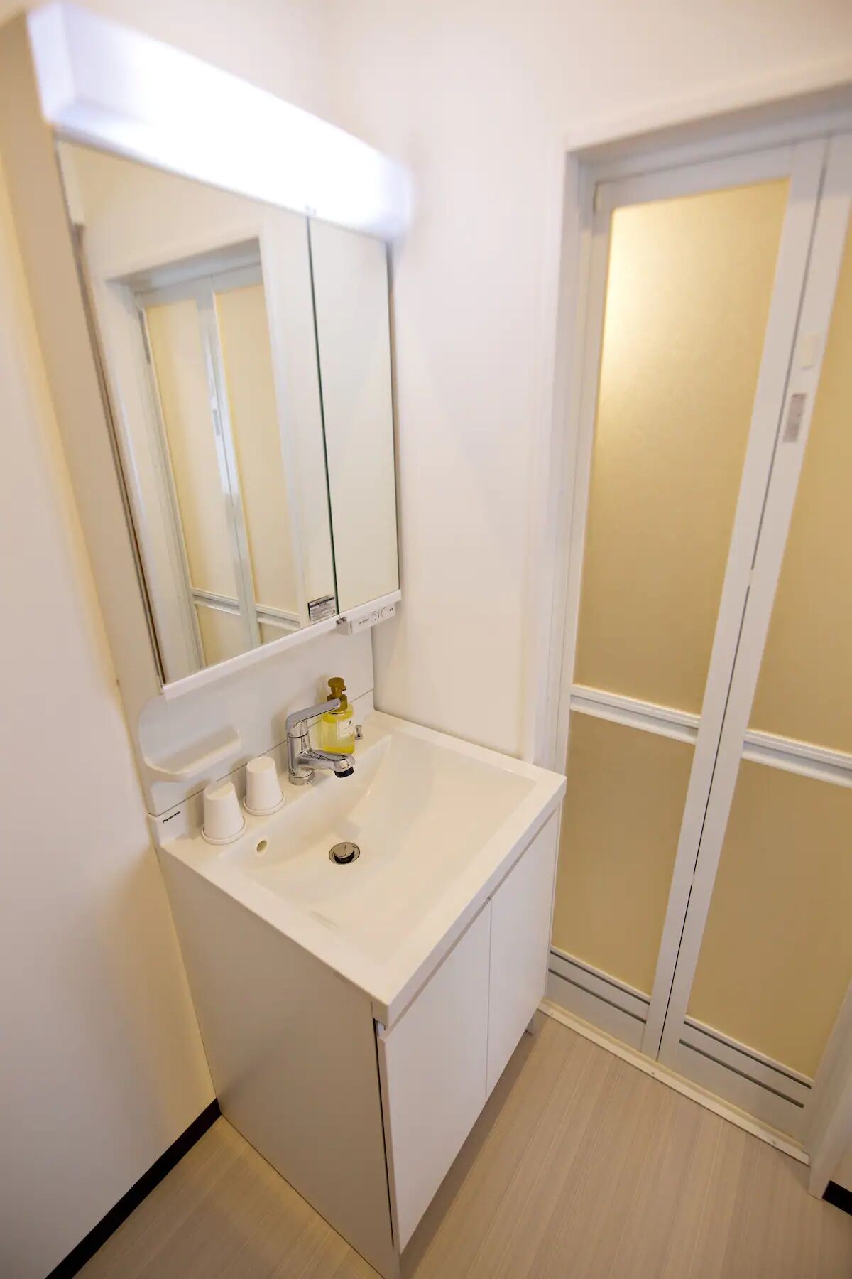 A small bathroom with a white sink, a mirror, and a cabinet.