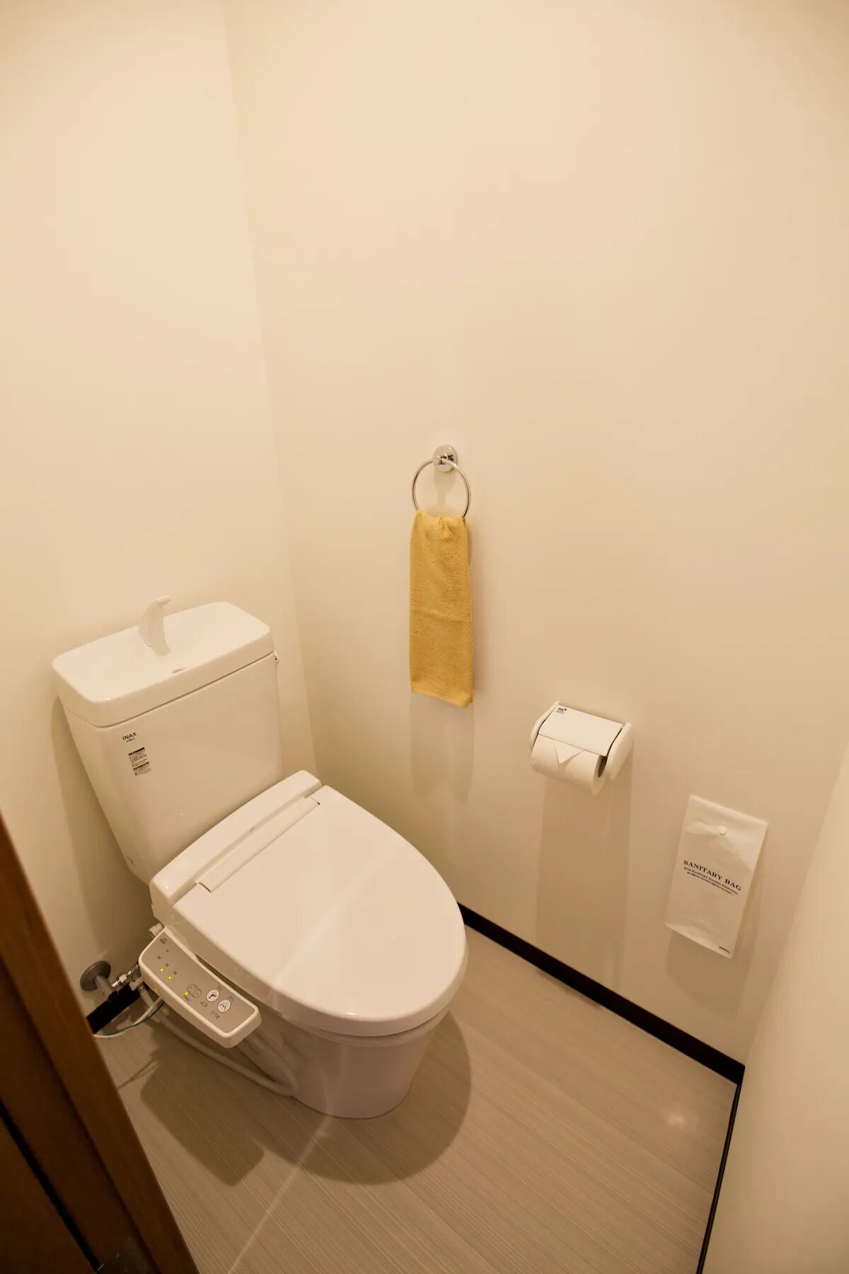 Ein modernes Badezimmer mit Toilette, einem Händetrockner und einem Spender für Hygienebeutel.