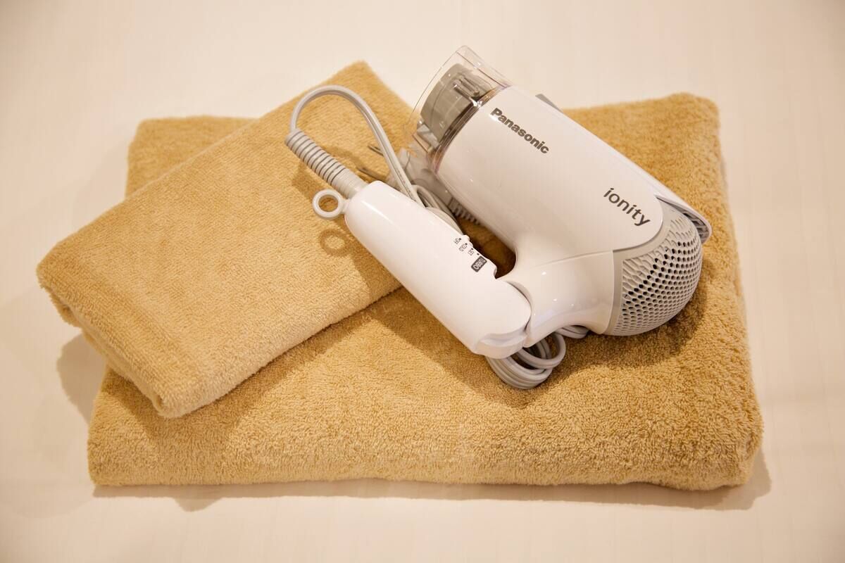 A Panasonic ionity hair dryer and a beige towel on a white surface.