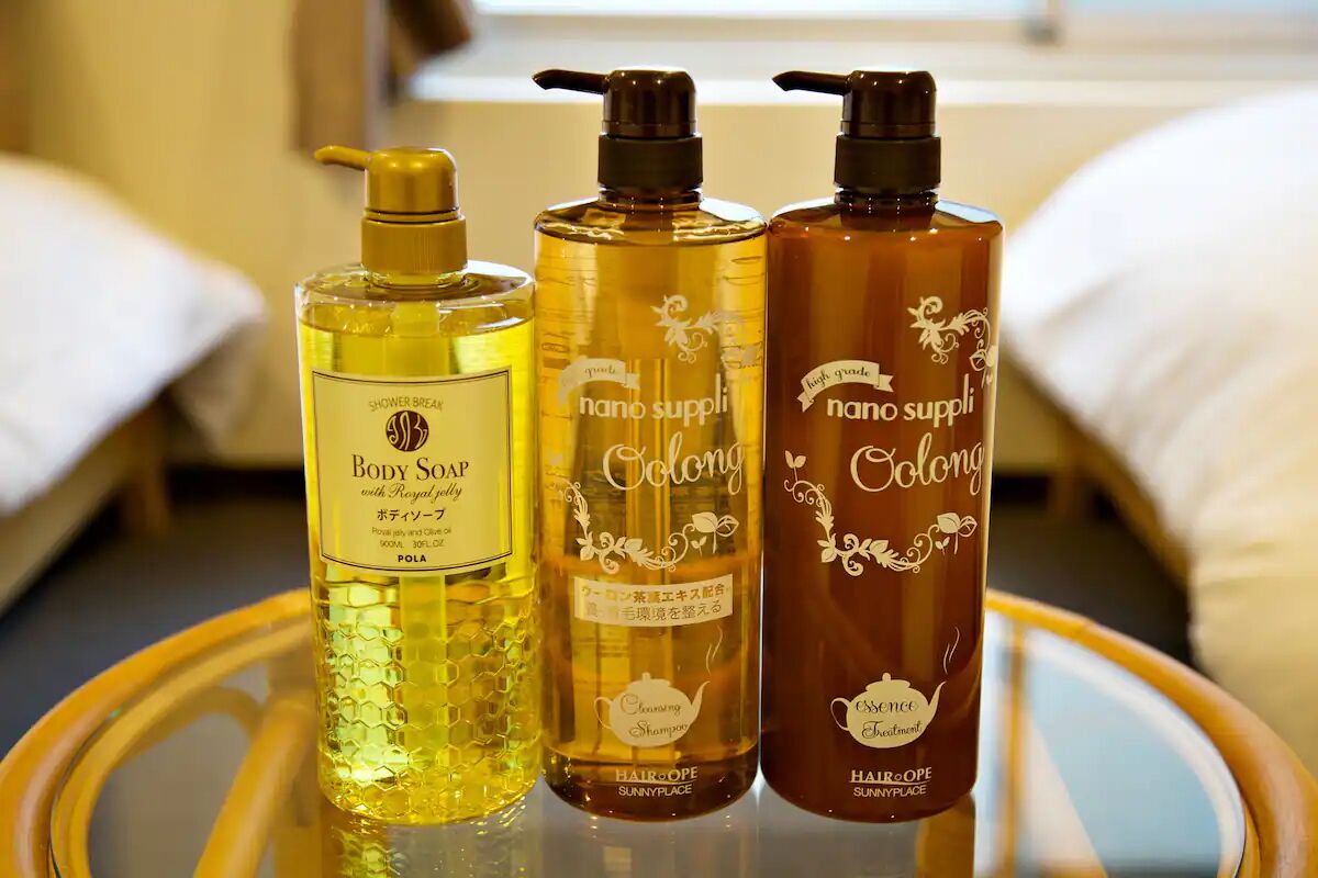 Three bottles of body soap on a round table in a hotel room.
