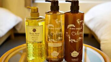 Three bottles of body soap on a round table in a hotel room.
