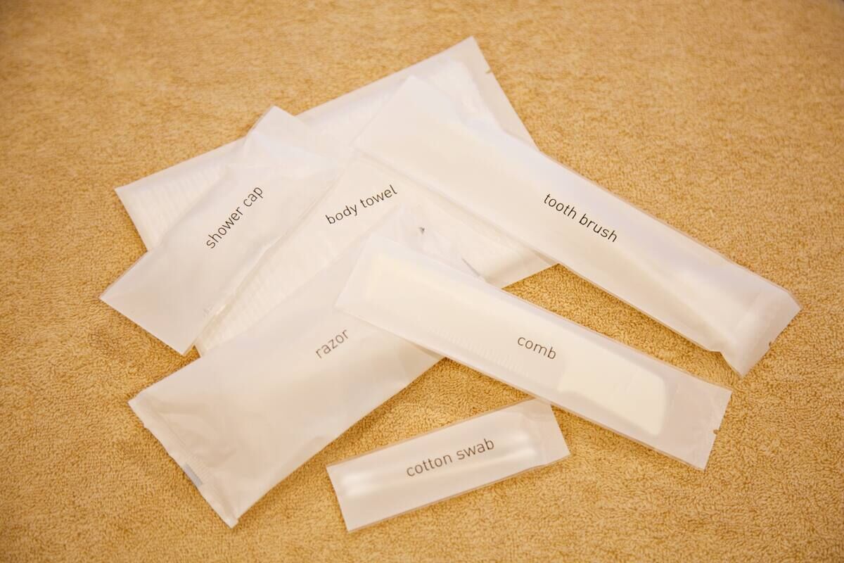 Diversos artículos de tocador como gorro de ducha, toalla de baño, cepillo de dientes, maquinilla de afeitar, peine y bastoncillos de algodón.