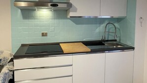 A compact kitchen with a stove, sink, and white cabinets. - Alghero Lido sunny beach apartment ☀️ (Alghero)
