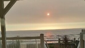 A wooden deck with a view of the ocean and a sunset.