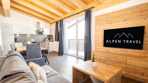 Een moderne woonkamer met een grijze bank, een houten salontafel en een tv waarop 