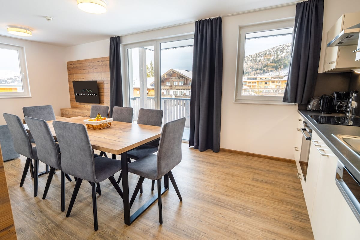 Eine moderne Küche mit Essbereich, großen Fenstern und Blick auf einen Berg.