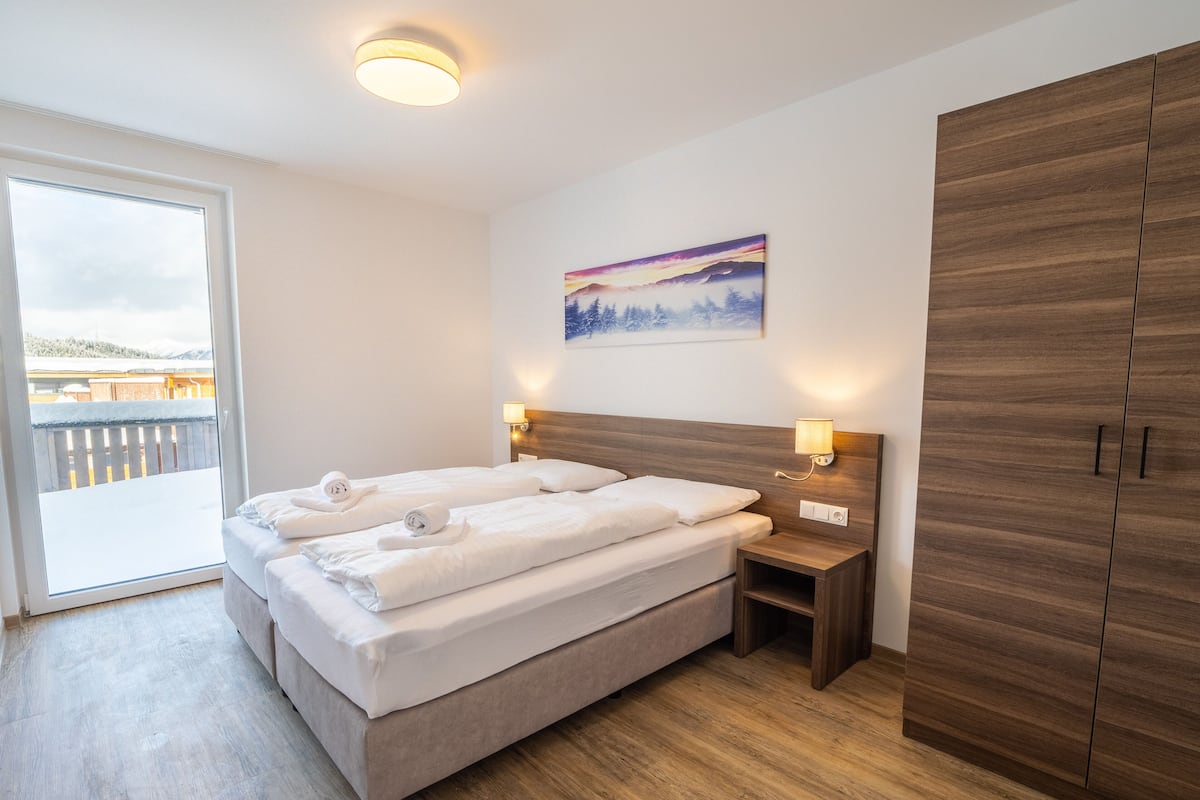 Ein Hotelzimmer mit einem Bett, zwei Nachttischen, einem Kleiderschrank und einem Bild an der Wand.