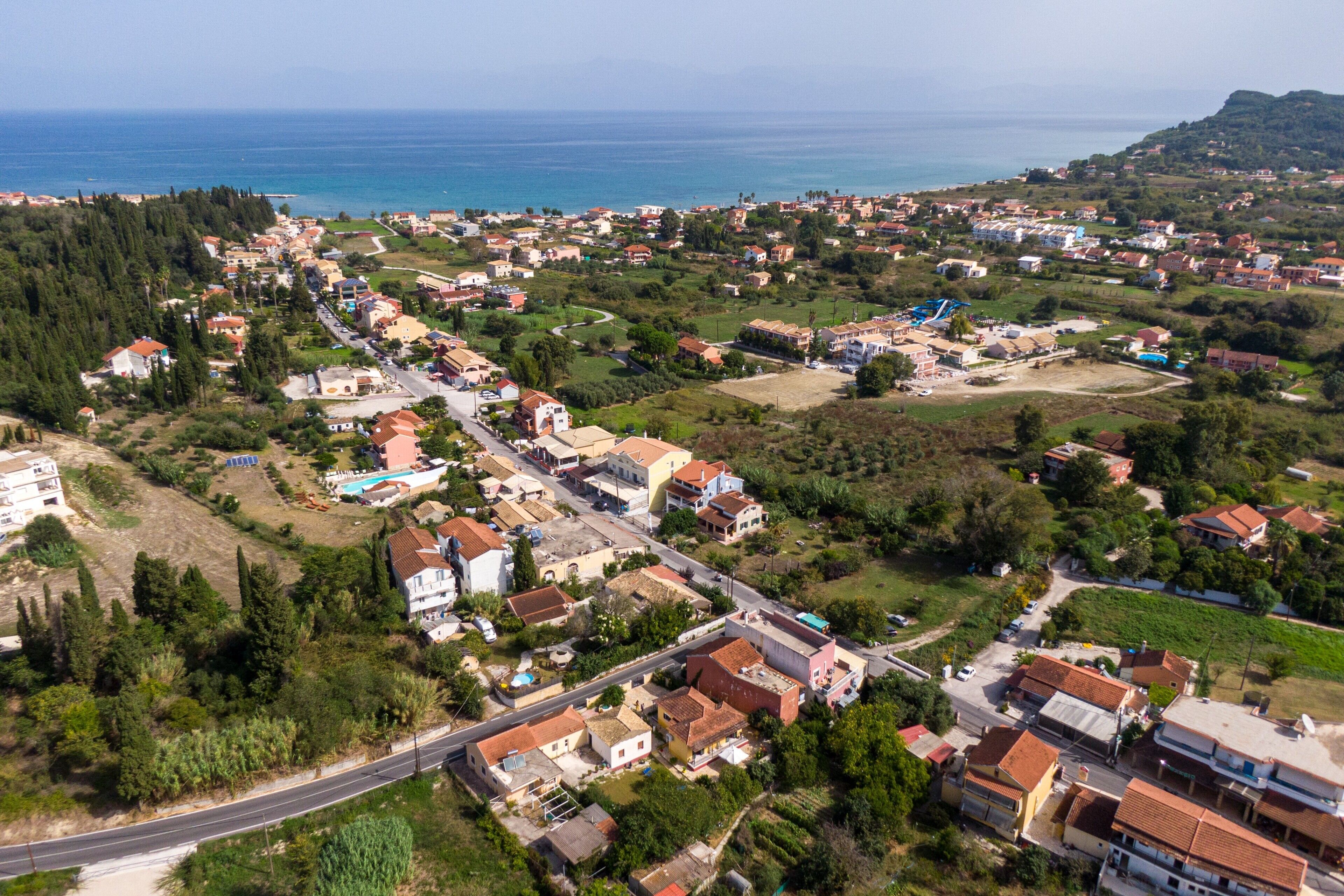An aerial view of a coastal town with houses, roads, and a beach.