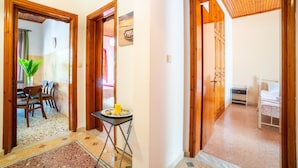 Un couloir avec un coin repas, une petite table avec une assiette, et une chambre à coucher avec un lit et une table de chevet.