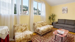 A living room with two floral sofas, a grey sofa, a red table with a white tablecloth, a red patterned rug, and a potted plant. - Holiday Home "Casal Do Farrobo" with Sea View, Private Terrace & Wi-Fi (Funchal)