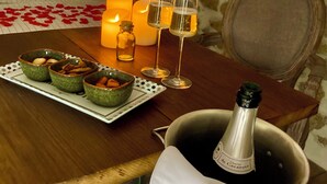 Un cuarto acogedor con una mesa de madera dispuesta para una cena romántica, con velas, copas y una botella de champán.