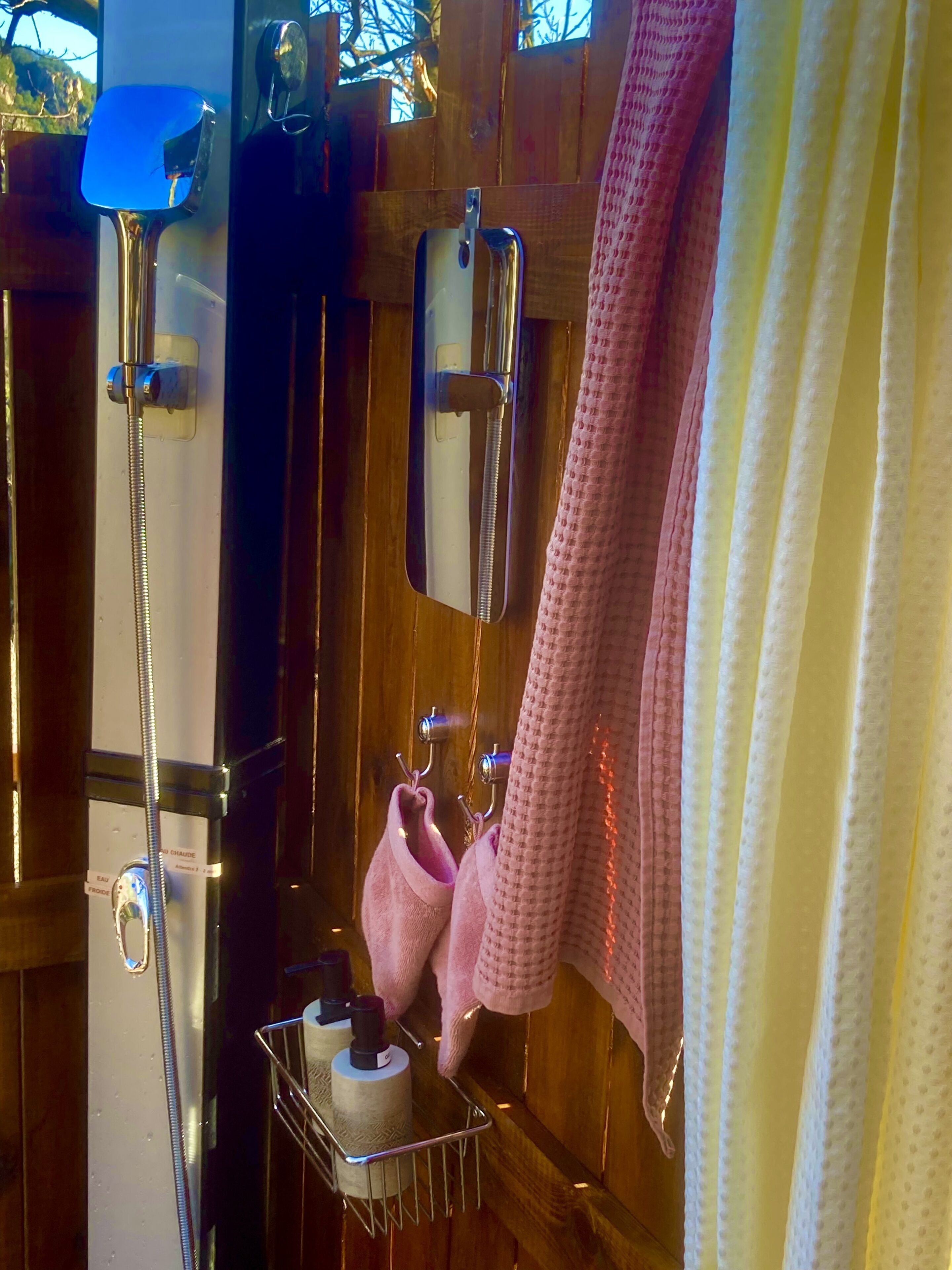 Une salle de bain avec une porte en bois, un porte-serviettes avec des serviettes roses et une étagère en métal contenant des articles de toilette.