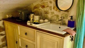Una pequeña cocina americana con encimera de madera, un lavamanos y un espejo.