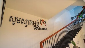 A staircase with a black railing and a welcome sign above it. - MarvelInn Siem Reap (Siem Reap)