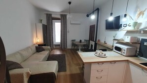 A compact living space with a sofa, a small dining table, a kitchenette with a microwave, and a TV. - Detached house St. George in the heart of the country (Vallata)