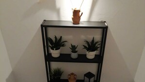 A black metal shelf with potted plants and a vase on a white wall. - Detached house St. George in the heart of the country (Vallata)