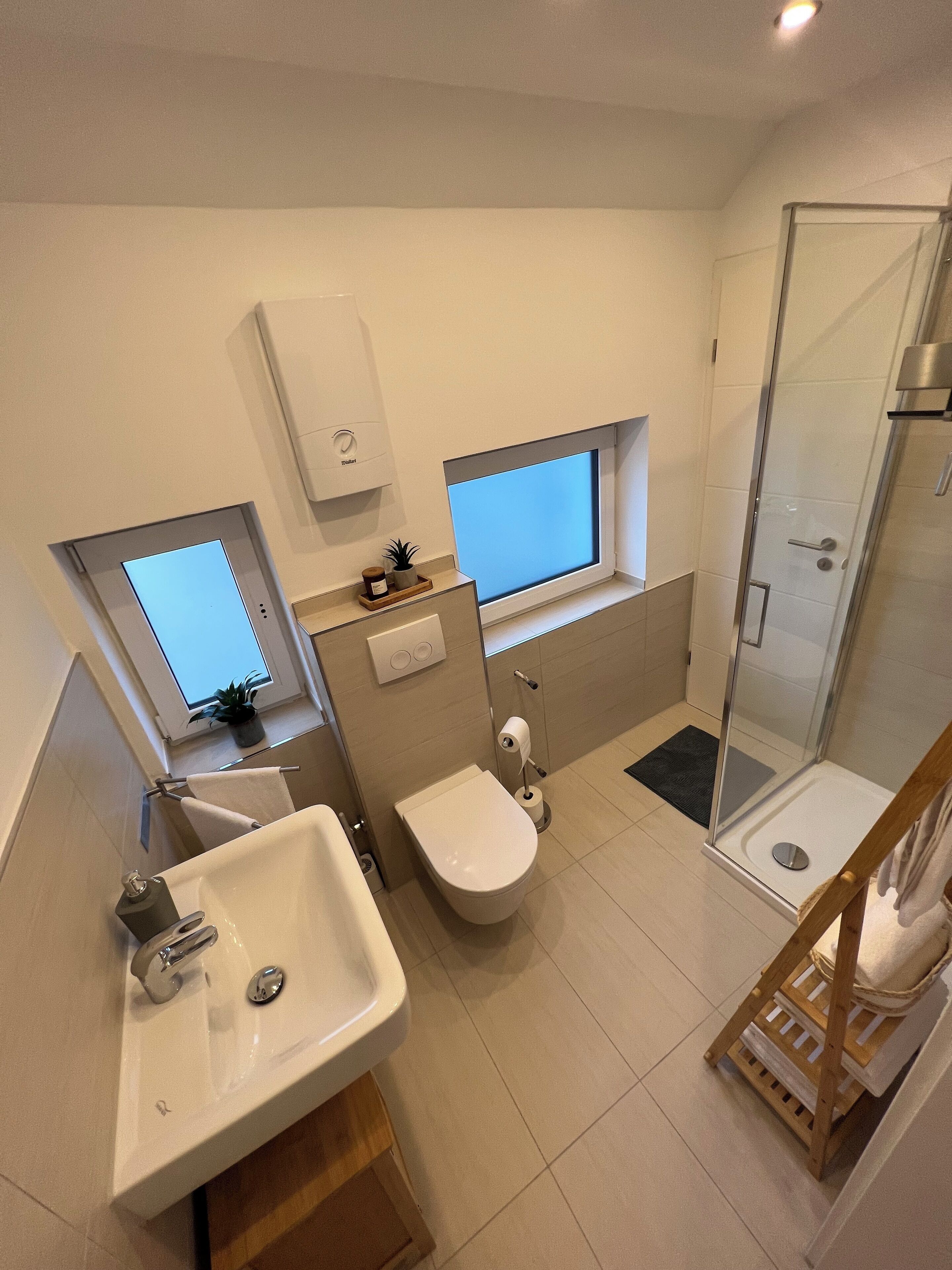 A modern bathroom with a sink, toilet, bidet, and glass shower enclosure.