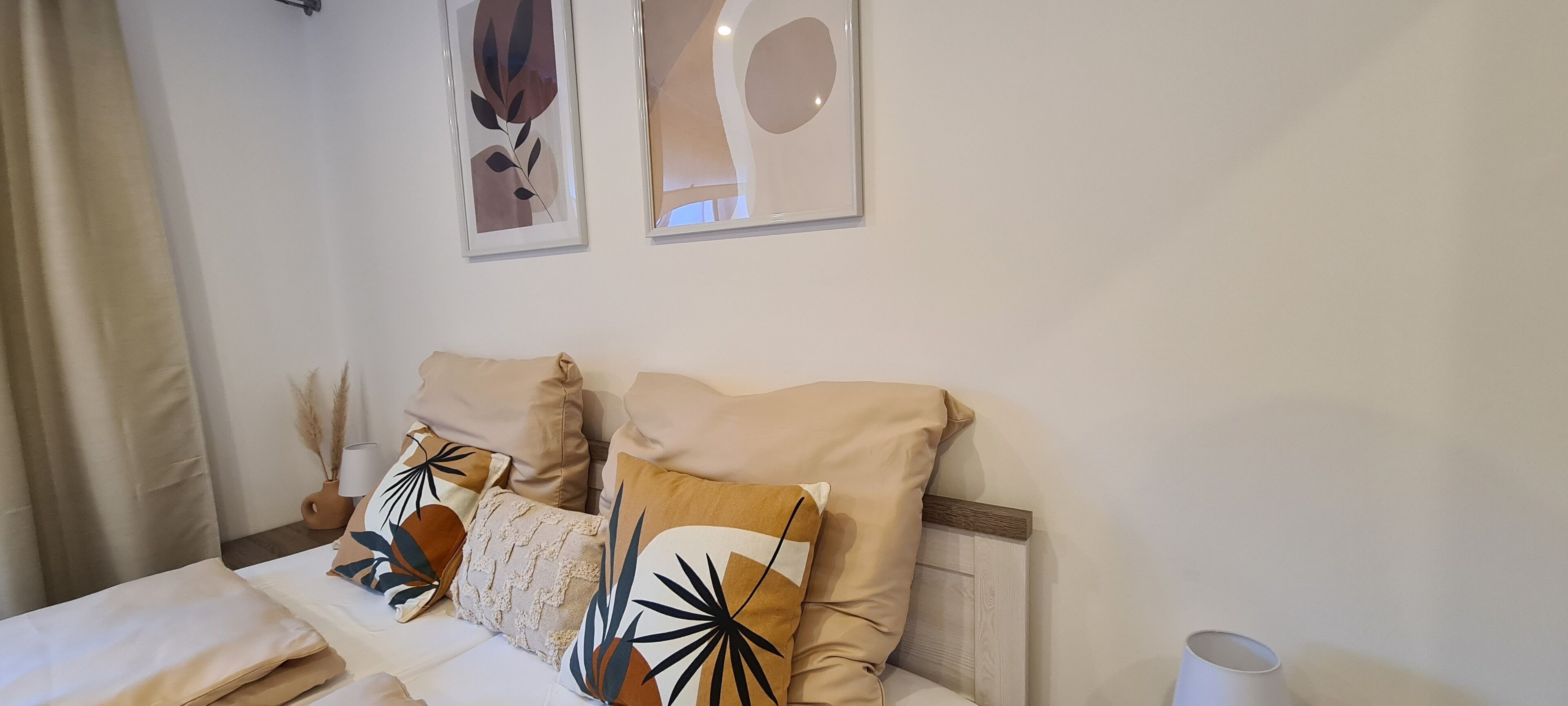 A neatly arranged bedroom with a bed, pillows, a bedside table, and wall art.
