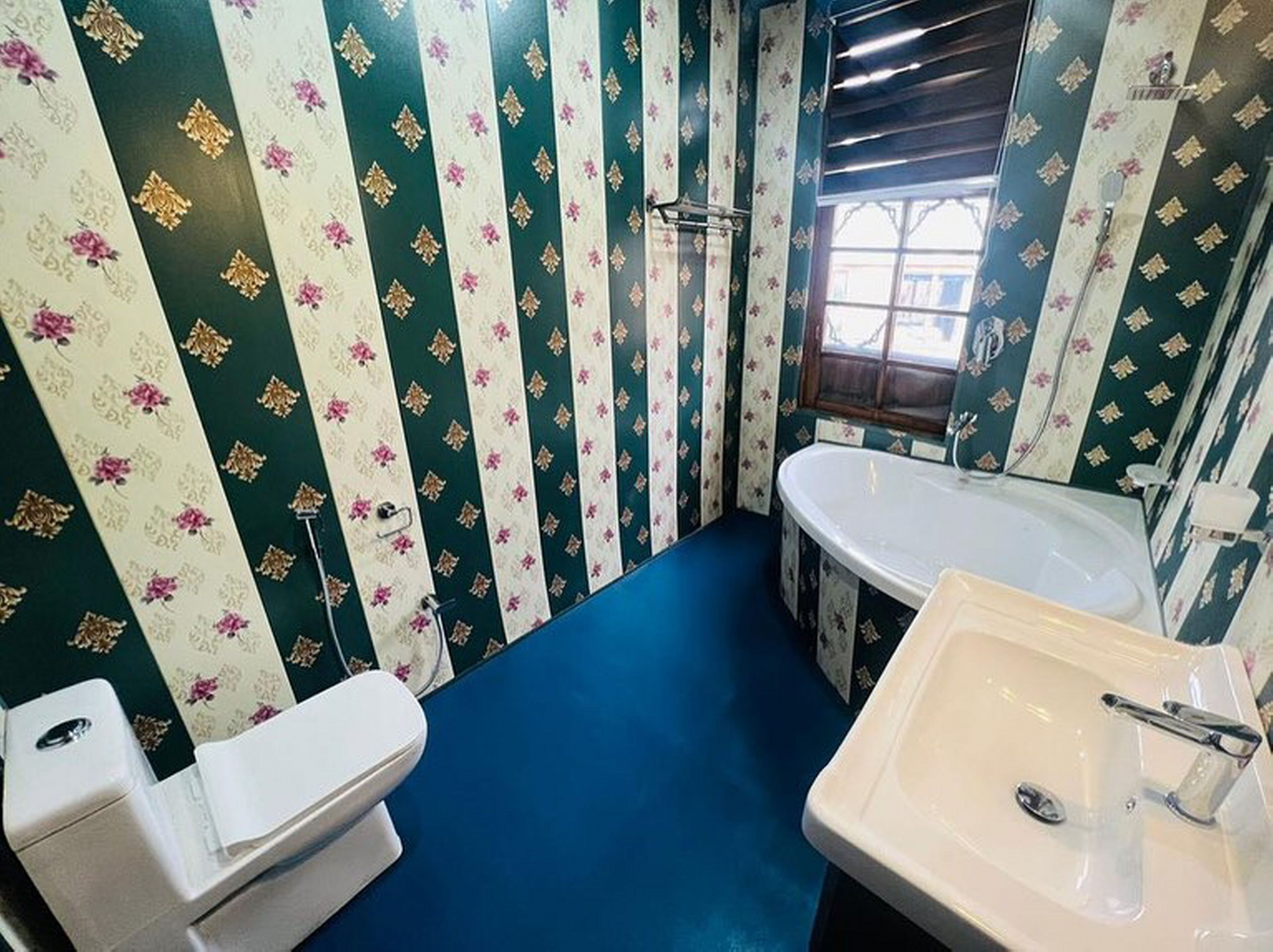 A bathroom with a toilet, sink, and bathtub. The walls have a striped floral pattern.
