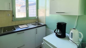 Une petite cuisine équipée d’une fenêtre, d’un évier, d’une machine à café et d’une bouilloire.