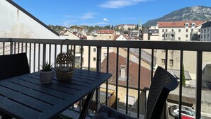 Un balcon avec une table, des chaises et un pot de fleurs.