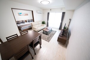 A modern living room with a sofa, a dining table, and a TV.