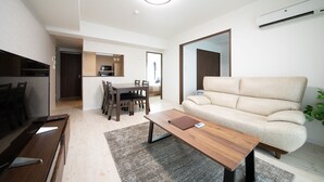 Una sala de estar moderna con un sofá, una mesa de centro, un comedor con sillas y una cocina al fondo.
