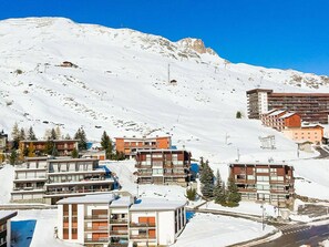 A snow-covered mountain town with modern buildings, including a hotel with multiple floors and balconies, set against a clear blue sky. - 2-Room Apartment 4 People Comfort with Wifi in Tignes (Tignes)