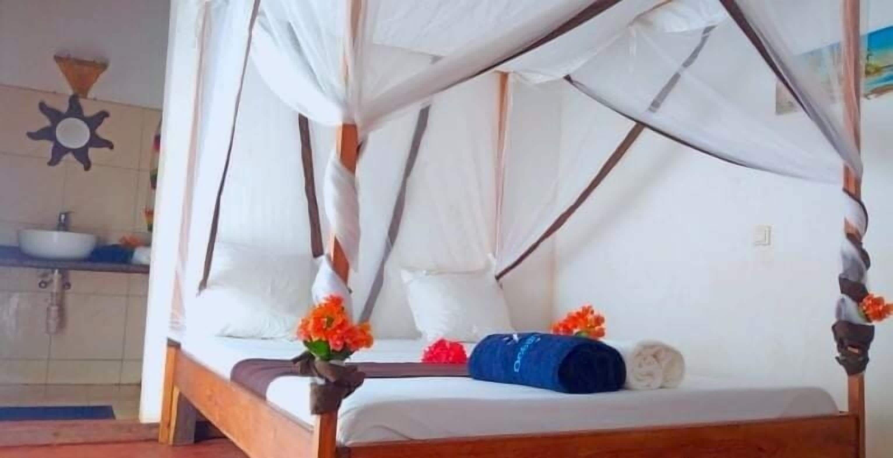 Een bed met hemel, een blauwe handdoek en oranje bloemen.