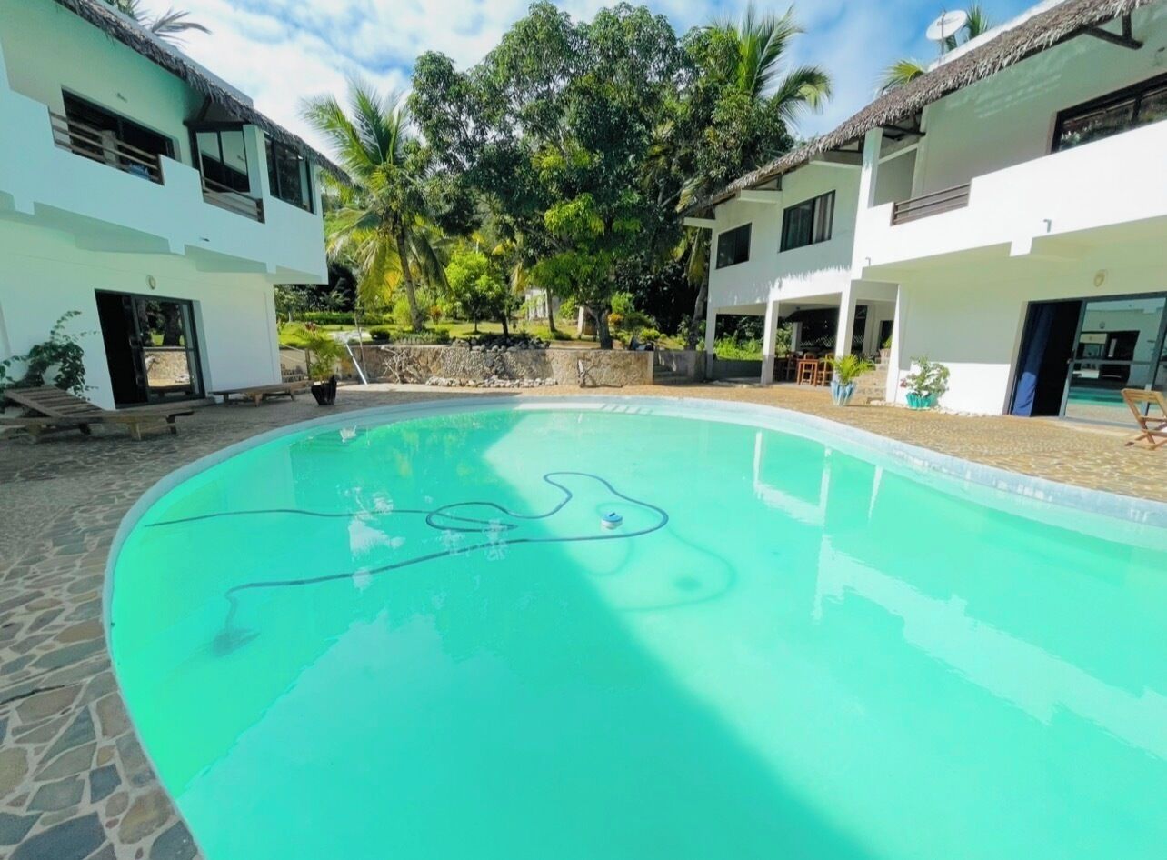 A swimming pool with a clear water line, surrounded by a stone patio.