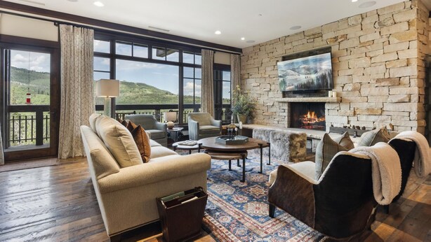 Un salón comedor espacioso con chimenea de piedra, ventanas amplias que ofrecen vistas al exterior y asientos cómodos.