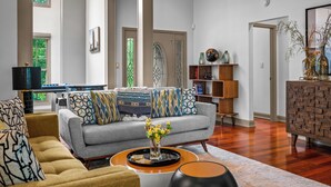 A spacious living room with a grey sofa, a yellow armchair, and a coffee table with a vase of flowers. A wooden bookshelf and a brick-patterned cabinet are visible in the background. - Private Forest House Near Smoky Mountain /Shopping (Sevierville)