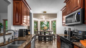 A modern kitchen with granite countertops, stainless steel appliances, and wooden cabinetry. - Private Forest House Near Smoky Mountain /Shopping (Sevierville)