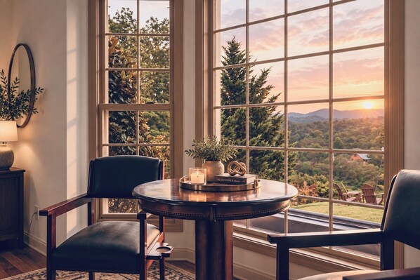 A room with a round table, two chairs, a potted plant, a candle, and a book titled 'The Kinfolk Home'.
