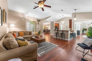 Relax in this spacious living area with a large sofa and coffee table, surrounded by a rug and pendant lighting.